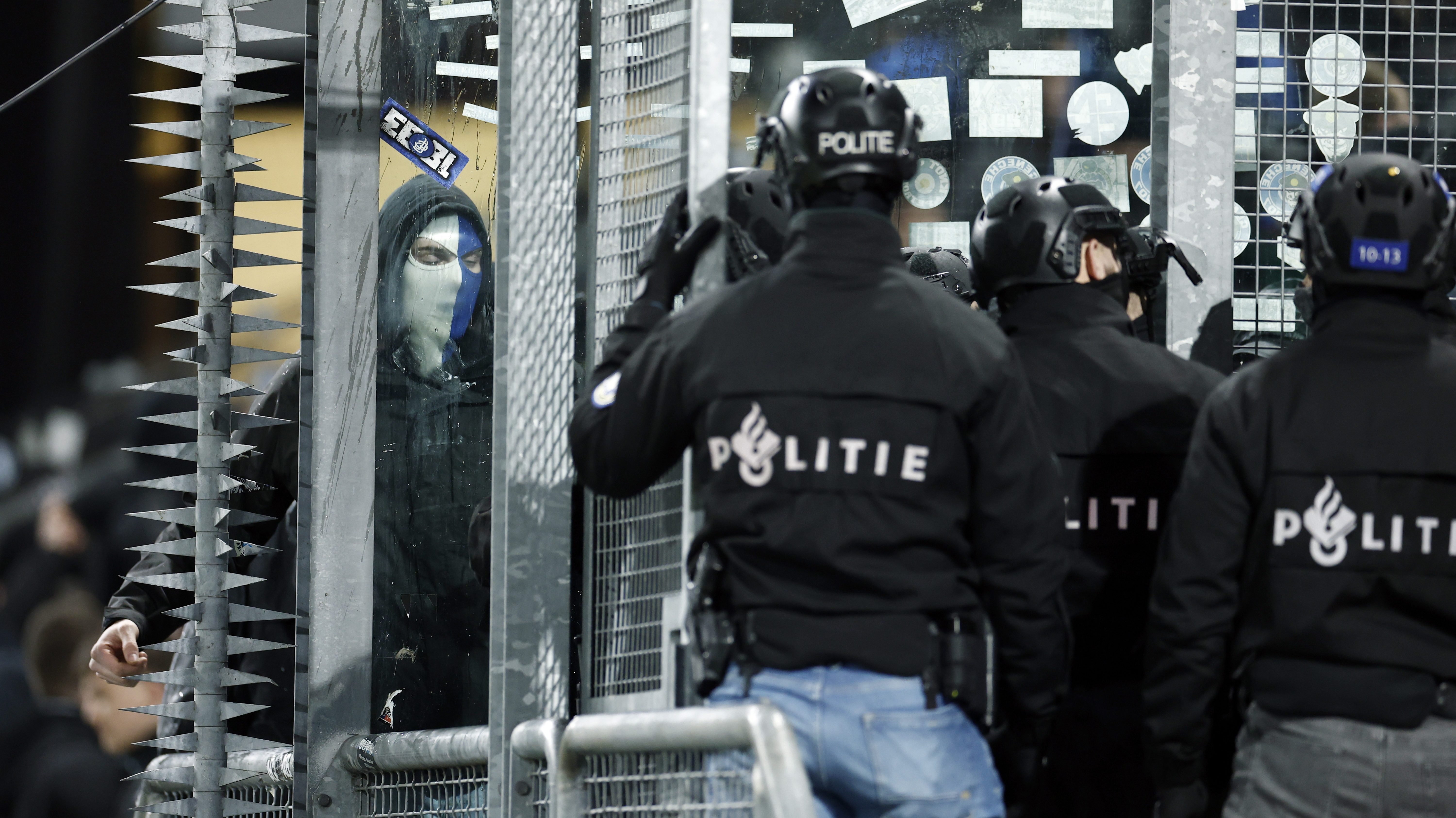 A Genk szurkolójával farkasszemet néző rohamrendőr.